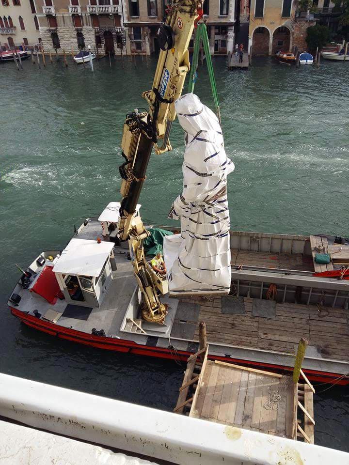 Moving a statue using a vessel equipped with a crane.