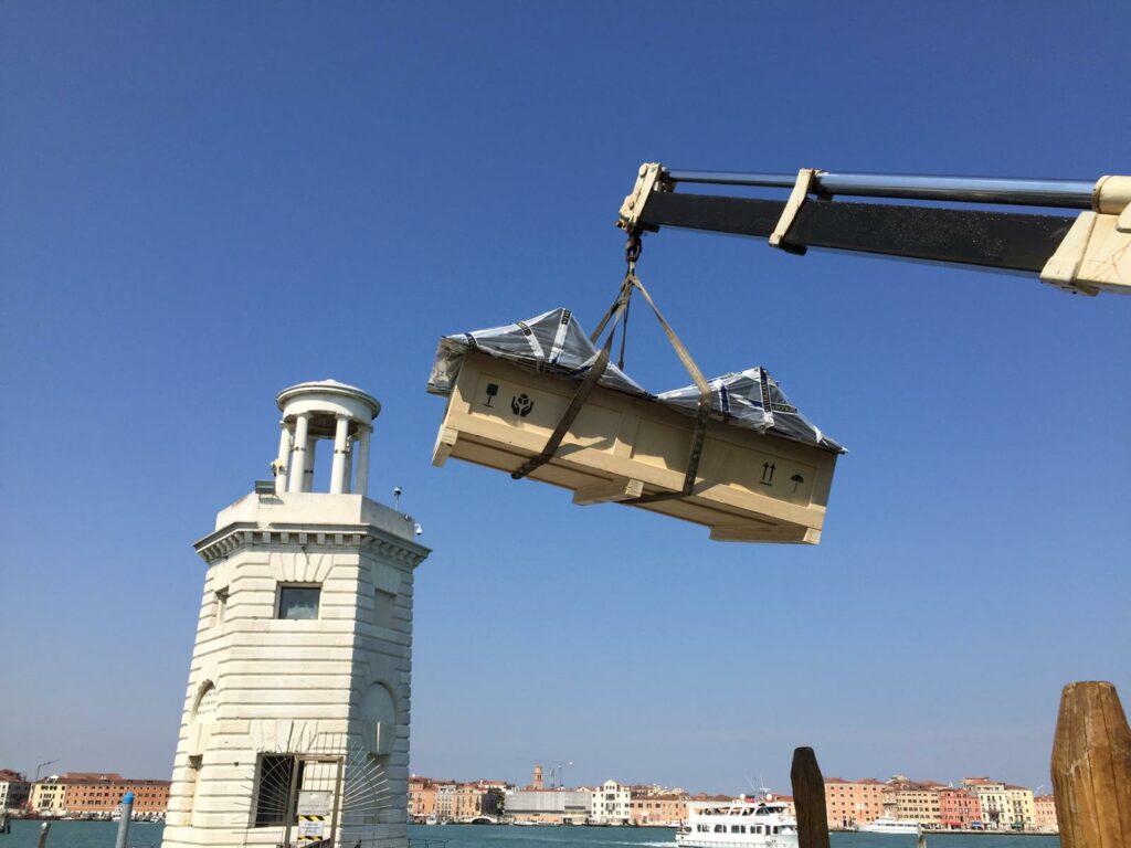 Packing a work of art in a protective crate and transporting it by boat equipped with a crane for handling.