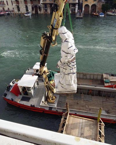 Moving a statue using a vessel equipped with a crane.