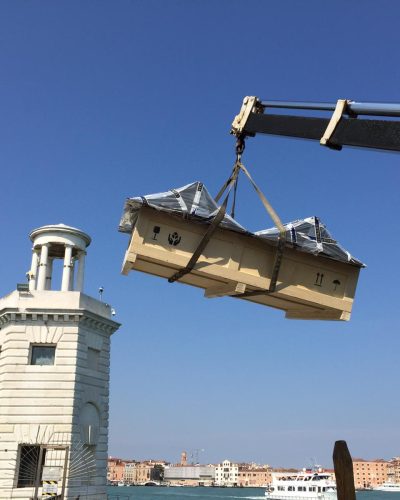 Packing a work of art in a protective crate and transporting it by boat equipped with a crane for handling.
